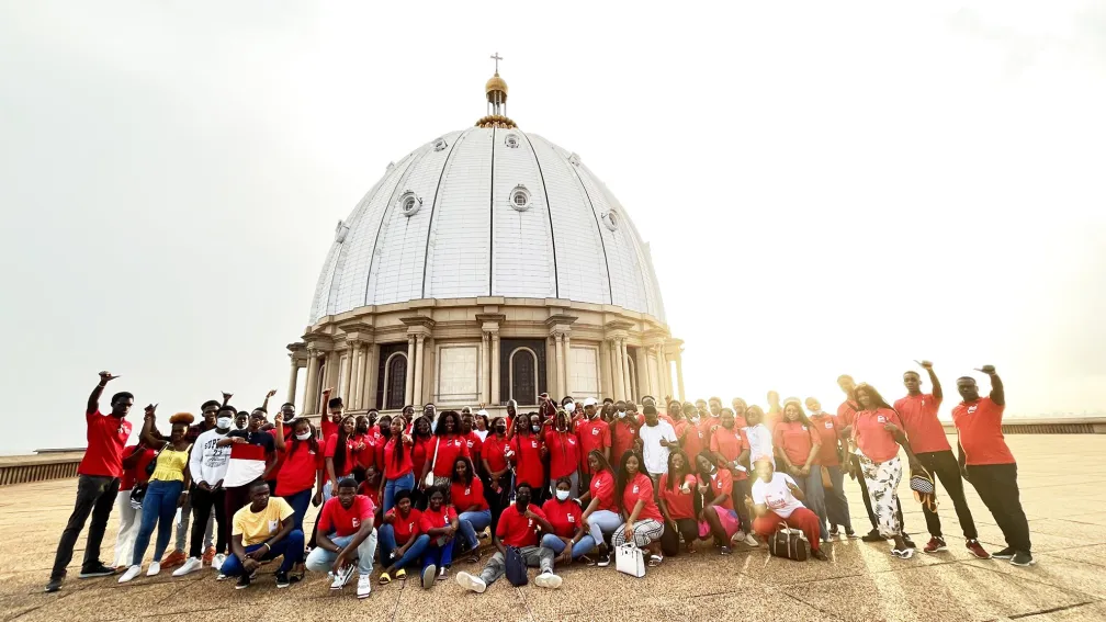 Groupe de personnes en rouge devant un grand bâtiment en forme de dôme.