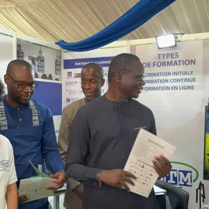 Des personnes discutant à une exposition, tenant des brochures.