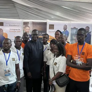 Groupe de personnes souriantes à une exposition, certains portent des t-shirts orange.